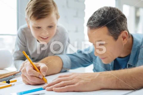 Curious boy watching his father draw a blueprint Stock Photos