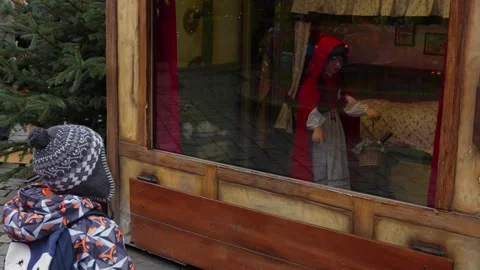 Curious boy in winter jacket and backpack examines fairy-tale window Stock Footage 296198728