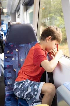 Curious boy writing by the train window during travel, focused Stock Photos