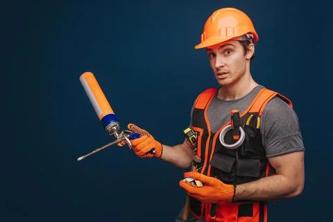 Curious builder is having equipment in arm, isolated over blue background Stock Photos