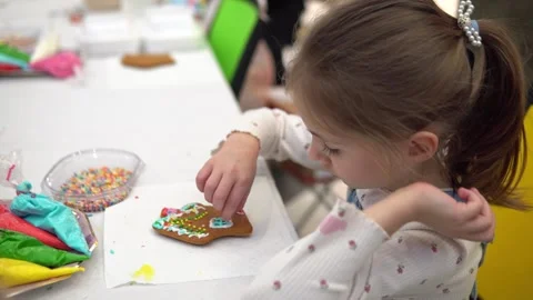 A Curious Child is Enthusiastically Decorating a Gingerbread Cookie Stock Footage 280410025