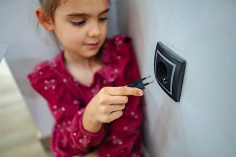 Curious child explores safe electrical outlet in a bright indoor space during Stock Photos
