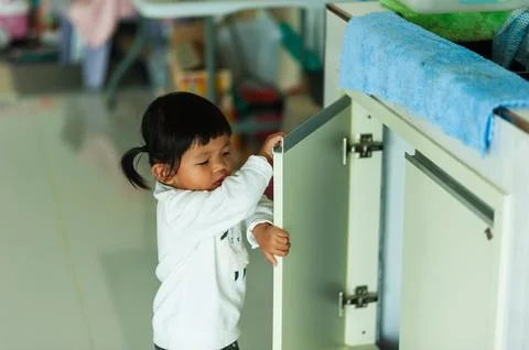 Curious child exploring kitchen cabinets home environment candid moment pla.. 写真素材