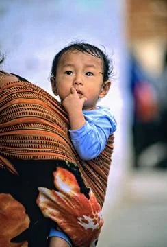 Curious child looks around while being carried in Bhutan Photos