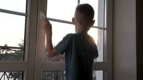 A curious child looks out the window at sunset Video stock 297254192