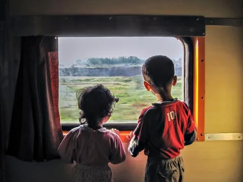 Curious children watching moving objects through the window of moving train Stock Photos