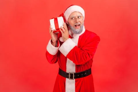 Curious elderly man with gray beard wearing santa claus costume holding and s Foto stock