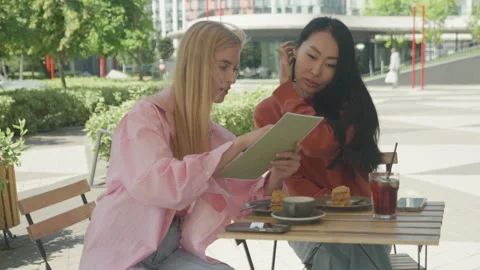 Curious Friends Deciding What To Order At Trendy Outdoor Cafe Видео 313843087