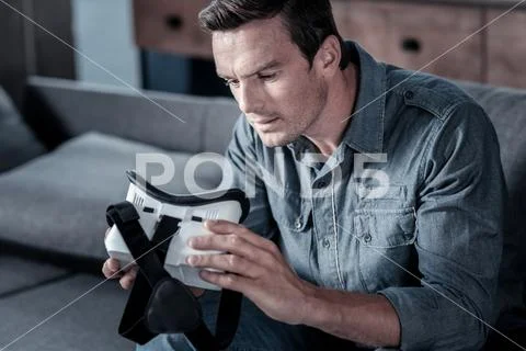 Curious gentleman looking at virtual reality goggles Stock Photos