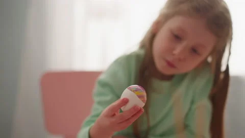 Curious girl looks at Easter egg with marbling patterns Stock Footage 172542157