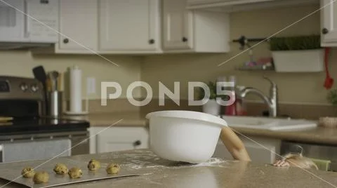 Curious girl reaching for bowl of cookie dough on kitchen counter Stock Photos