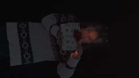 Curious girl in sweater opens magic box with light. Vertical orientation video Stock Footage 220157717