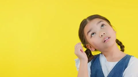 Curious Girl Thinking and Pointing to Head on Yellow Background Stock Footage 321723351