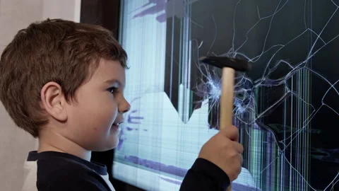 The Curious Handyman: A Young Boy Fixing a Broken Screen with a Hammer Stock-Footage 257581075