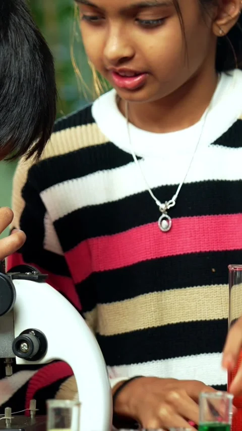 Curious Indian kids using a microscope and test tubes at school Stock Footage 343214469
