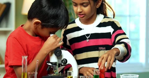 Curious Indian kids using a microscope and test tubes at school Stock Footage 343216131