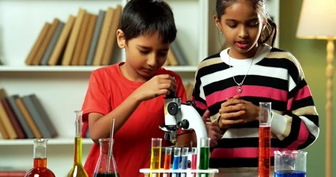 Curious Indian kids using a microscope and test tubes at school Stock Footage 343216134