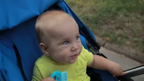 Curious infant boy sitting in pram outdoors Stock Footage