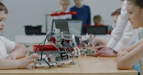 Curious kids working on a programable robot during robotics class at school Video stock 108886317