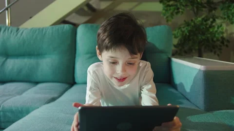 Curious Little Kid Boy Using Digital Pad Entertainment Device Lying On Sofa Stock Footage 161964217