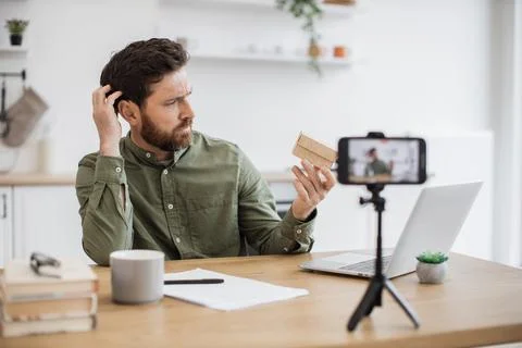 Curious man doing unpacking and live streaming at home Stock Photos