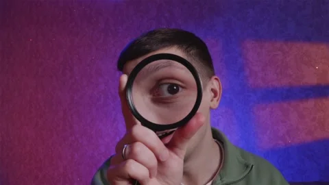 Curious man looking around through magnifying glass with joy Stock Footage 333756905