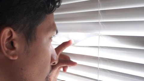 Curious man looking through venetian blind Video stock 328646337
