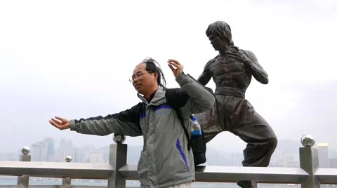 Curious man pose against Bruce Lee statue, Avenue of Stars, HongKong Stock Footage 49851260