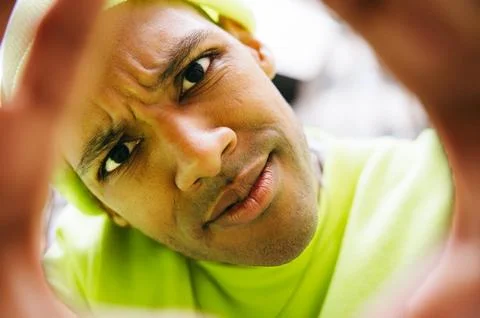 Curious multiracial man framed by hands looking at camera in city Stock Photos