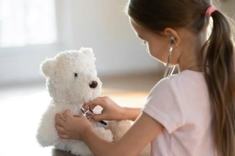 Curious small preschooler playing nurse patient with toy. Stock Photos