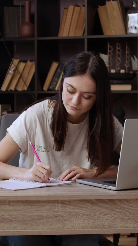 Curious student surfs the internet looking for information and takes notes with Stock Footage 305406916