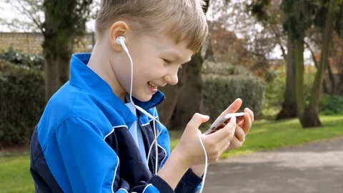 Curious teen boy with smart phone listening or talking while sitting in british Stock Footage