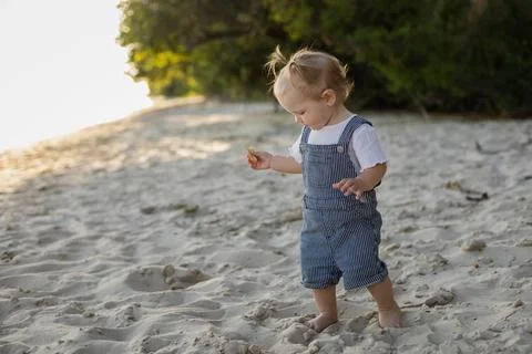 Curious toddler exploring a sandy beach during golden hour 스톡 사진