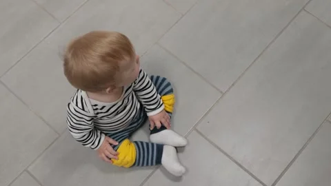 Curious toddler sitting on tile floor Stock Footage 337738614