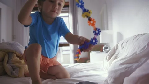 A Curious Toddler's Creative Exploration on a Cozy Bed Stock Footage 254916063