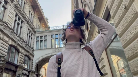 Curious traveler with camera walks under historic bridge in old European town, a Stock Footage 305380937