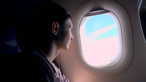Curious traveler watching bright clouds through airplane window seat during Stock Footage 344868437