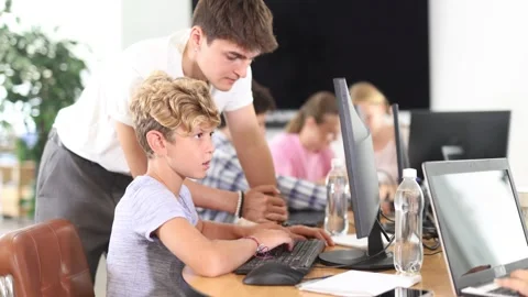 Curious underage boy engaged in IT training with help of teacher in computer Stock Footage 303669033