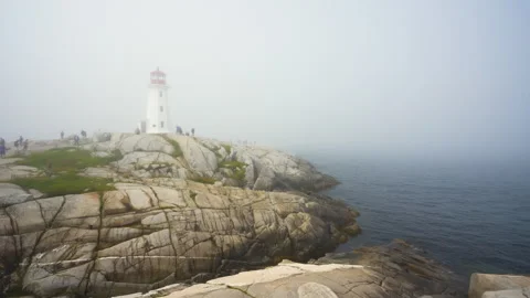 Curious visitors explore of Peggy's Cove Lighthouse on a foggy morning Stock Footage 284685257