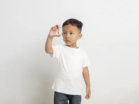 Curious young boy holding a small glass medical vial up to his eye to exami.. 写真素材