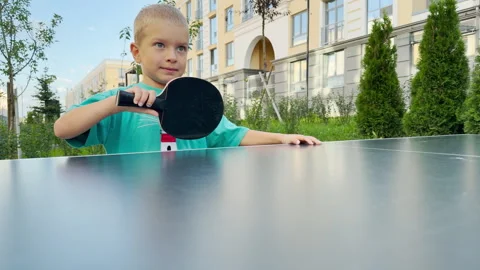 A curious young boy holds a black ping pong paddle with anticipation. Stock Footage 344967898