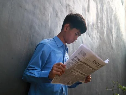 A curious young man focused on reading a newspaper Stock Photos