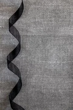 Curly black bow on gray texture background. Stock Photos
