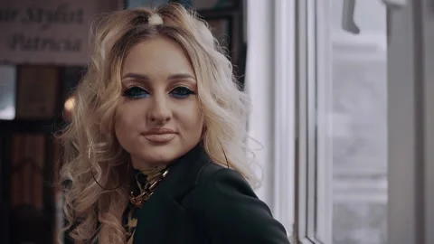 The curly blonde, with a shrill make-up, dressed in a jacket, displays an Stock Footage 157682329