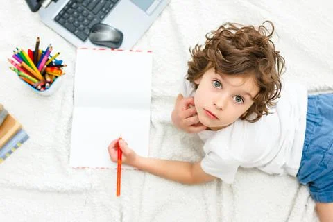 Curly boy is engaged at computer. schoolboy looks up, view into camera. Stock Photos