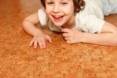 Curly boy lying on white floor at home and smiling. The concept of underfloor Stock Photos