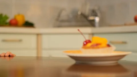 Curly boy peeking from the table and stealing cake with red cherry Stock Footage 125705908