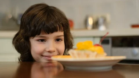 Curly boy peeking from the table and stealing cake with red cherry Stock Footage 125706367