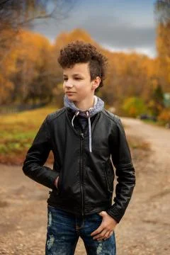Curly brown-haired boy with a mohawk hairstyle in a leather jacket on an autu Stock Photos
