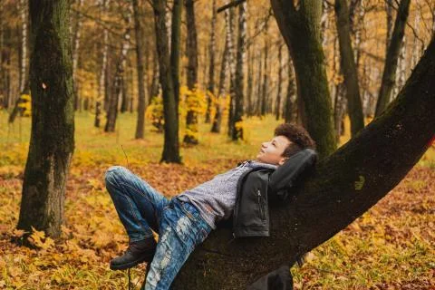 Curly brown-haired boy with a mohawk hairstyle in a leather jacket against th Stock Photos